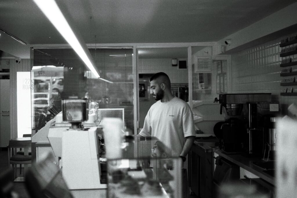 A barista in a cafe working with concentration, captured in black and white.